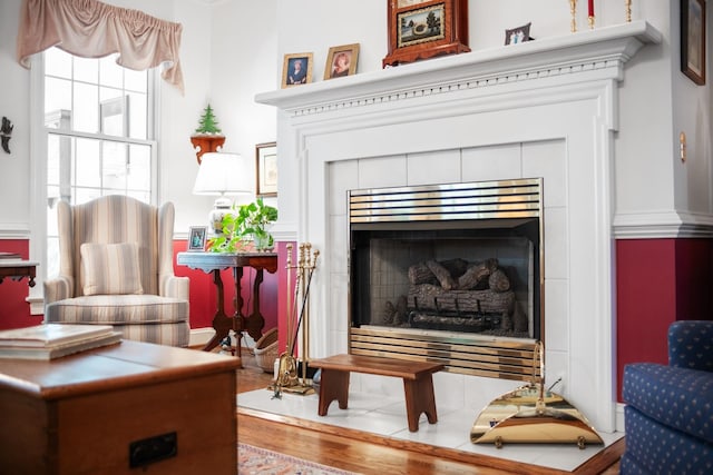 sitting room with a tiled fireplace and wood finished floors