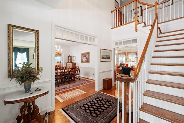 foyer entrance with stairway, a notable chandelier, a high ceiling, and wood finished floors