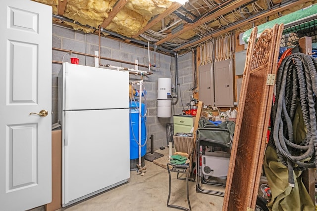 unfinished below grade area featuring electric panel and freestanding refrigerator