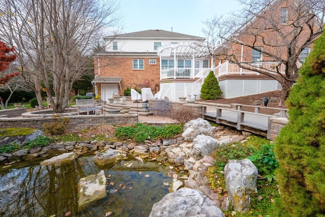 back of property with brick siding, stairs, a small pond, a pergola, and a patio