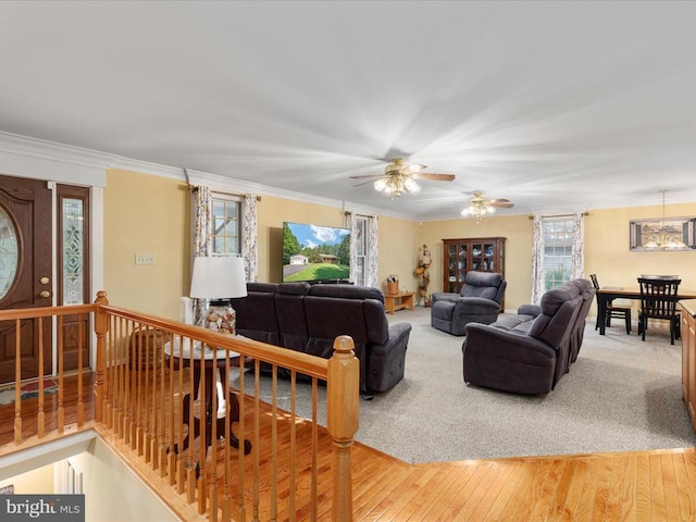 living room with wood-type flooring, ornamental molding, and ceiling fan