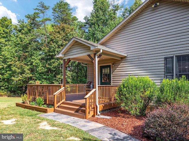 view of exterior entry featuring a wooden deck and a lawn