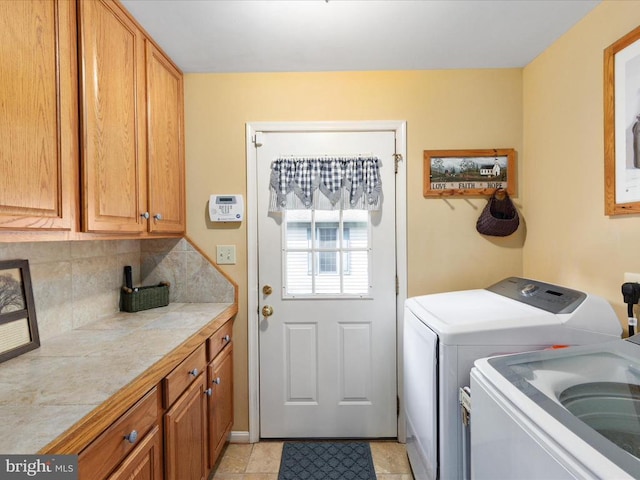 clothes washing area featuring cabinets, washing machine and dryer, and light tile patterned floors