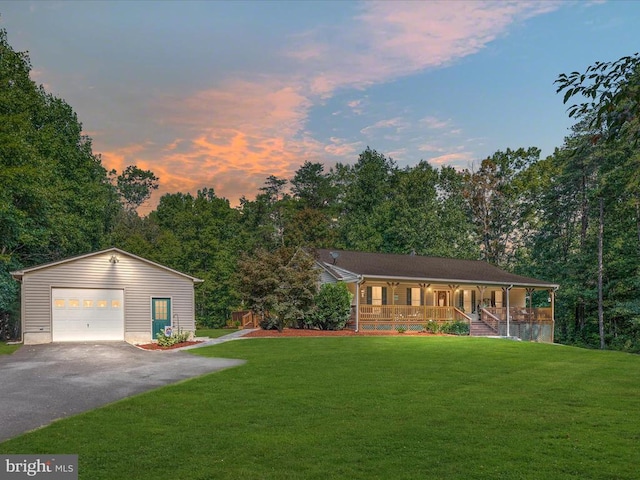 view of front of property featuring an outbuilding, a garage, a yard, and covered porch