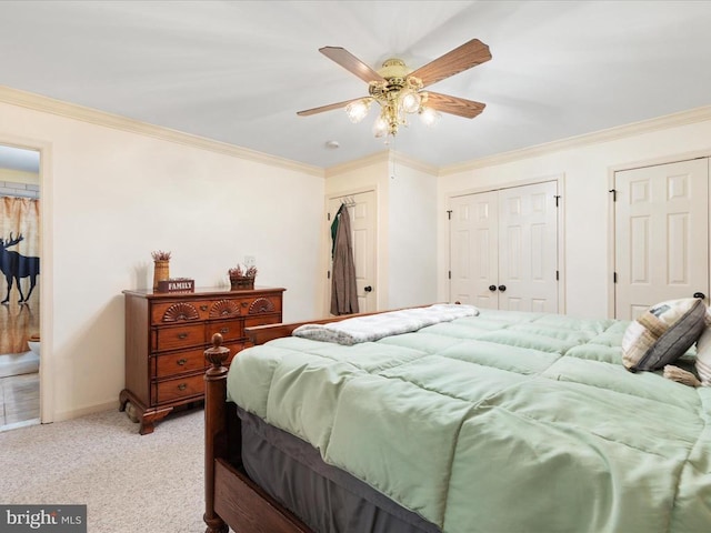 carpeted bedroom featuring crown molding, ceiling fan, and two closets