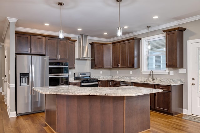 kitchen with stainless steel appliances, decorative light fixtures, a kitchen island, and wall chimney range hood