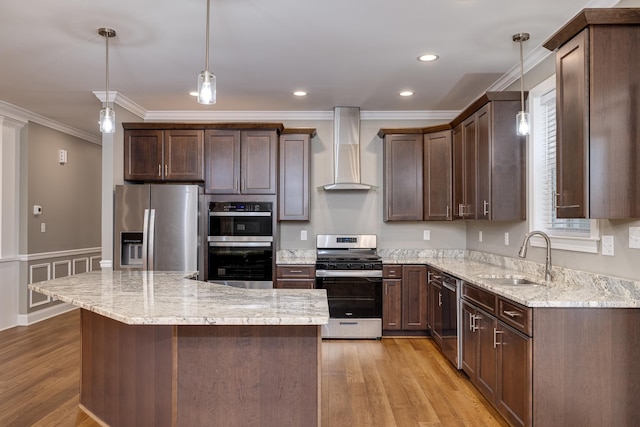 kitchen featuring sink, decorative light fixtures, a center island, stainless steel appliances, and wall chimney range hood