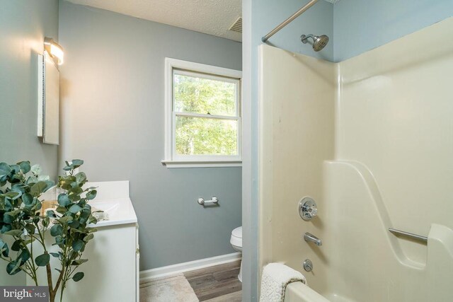 full bathroom with toilet, bathtub / shower combination, a textured ceiling, vanity, and hardwood / wood-style flooring