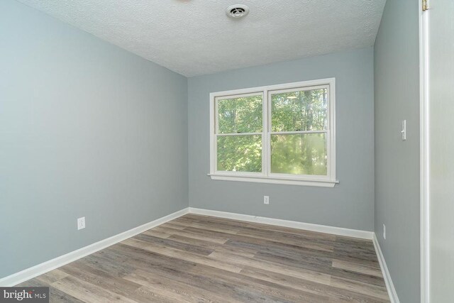 unfurnished room featuring hardwood / wood-style floors and a textured ceiling