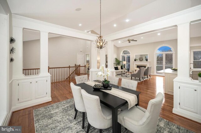 dining area featuring decorative columns, crown molding, ceiling fan with notable chandelier, and dark hardwood / wood-style flooring