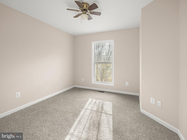 unfurnished room featuring carpet floors, visible vents, ceiling fan, and baseboards