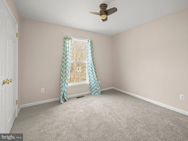 unfurnished room with a ceiling fan, carpet, visible vents, and baseboards