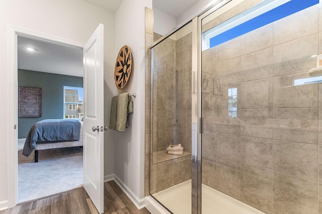 ensuite bathroom with baseboards, wood finished floors, ensuite bathroom, and a stall shower