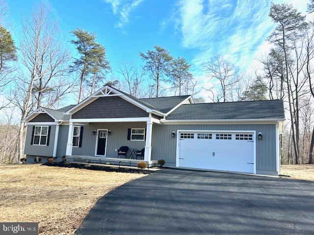 view of front facade featuring a garage, a front yard, and a porch