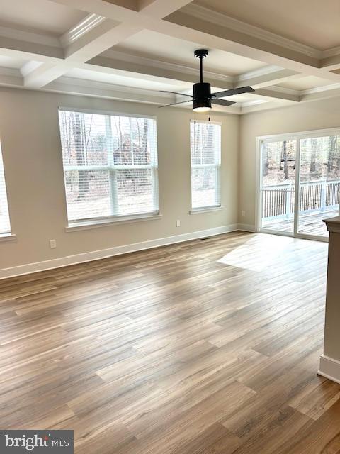 empty room featuring wood-type flooring, ornamental molding, coffered ceiling, ceiling fan, and beam ceiling