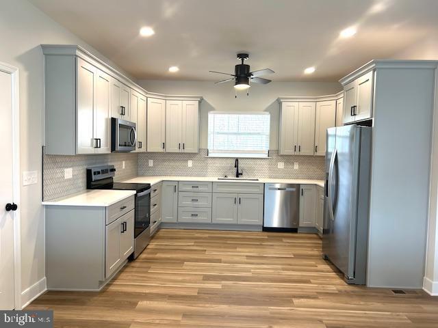 kitchen featuring stainless steel appliances, gray cabinets, sink, and light hardwood / wood-style flooring