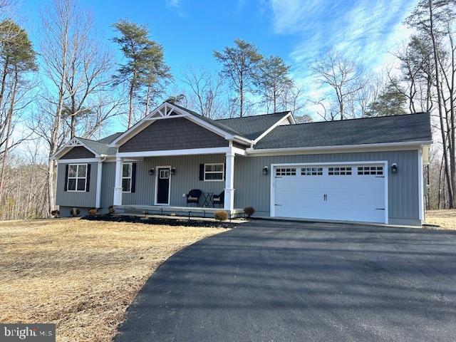 ranch-style home with a garage, a porch, and a front yard