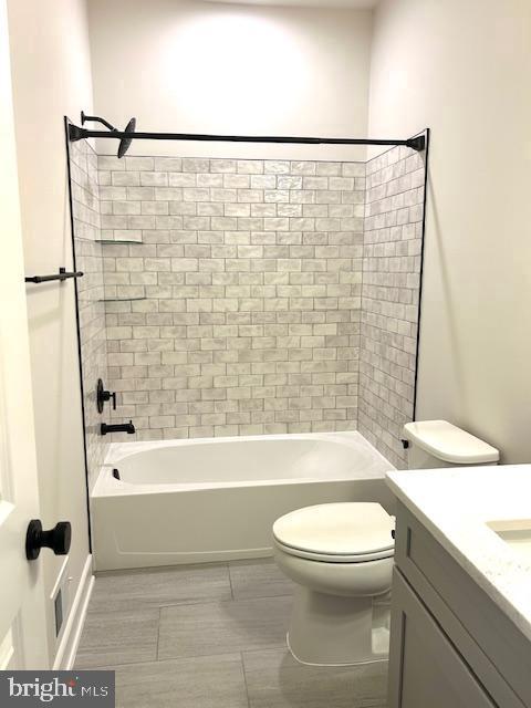 full bathroom with vanity, tiled shower / bath, and toilet