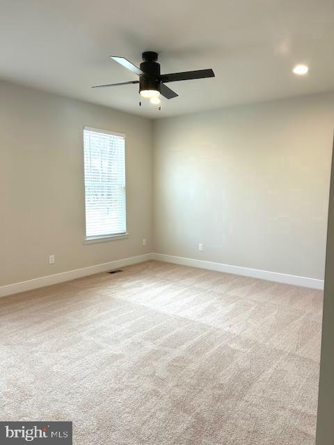 carpeted spare room featuring ceiling fan