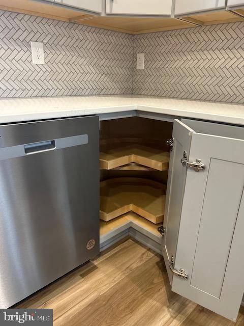 details with backsplash, stainless steel dishwasher, and light wood-type flooring