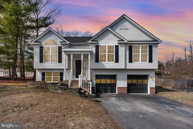 bi-level home with fence, a garage, and driveway