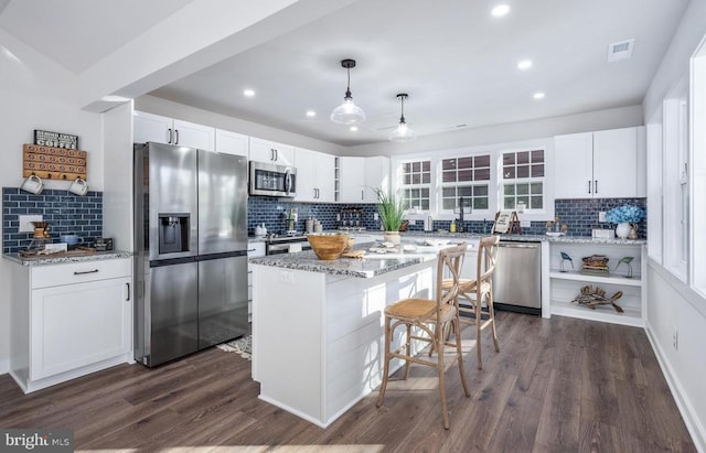 kitchen with stainless steel appliances, white cabinets, visible vents, and dark wood-style floors