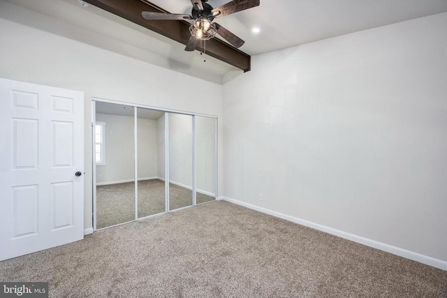 unfurnished bedroom with carpet floors, a closet, beamed ceiling, and baseboards