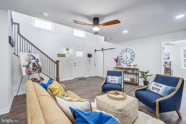 living area with baseboards, a barn door, stairway, and wood finished floors