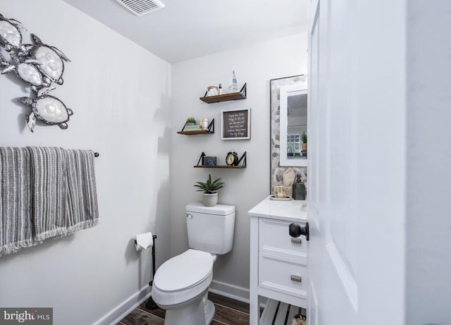 bathroom featuring toilet, wood finished floors, vanity, visible vents, and baseboards