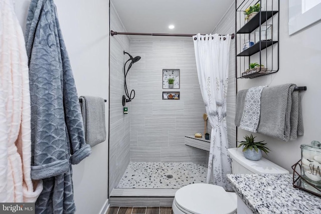 bathroom featuring vanity, a tile shower, and toilet