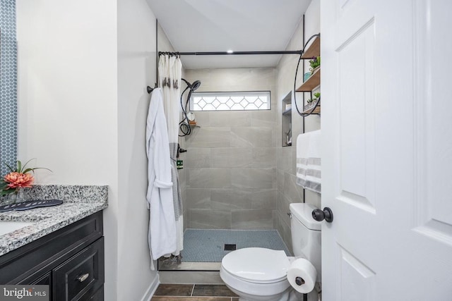 full bath with tiled shower, vanity, and toilet