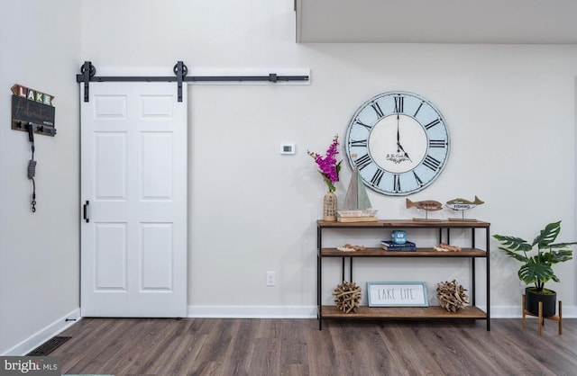 interior space featuring a barn door, wood finished floors, visible vents, and baseboards