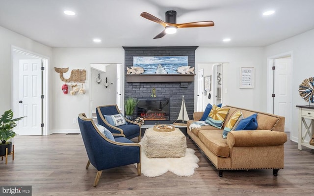 living room featuring recessed lighting, wood finished floors, a ceiling fan, baseboards, and a brick fireplace