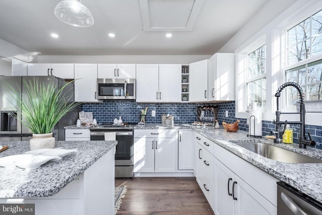 kitchen with dark wood-style flooring, open shelves, stainless steel appliances, white cabinetry, and a sink