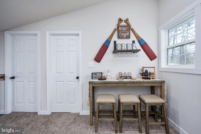 interior space featuring carpet floors, lofted ceiling, a dry bar, and baseboards