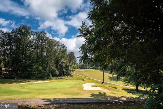 view of property's community with view of golf course and a lawn