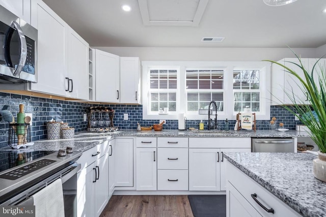 kitchen with visible vents, appliances with stainless steel finishes, dark wood-type flooring, white cabinetry, and a sink