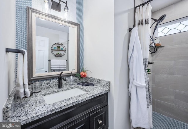 full bathroom featuring a tile shower and vanity