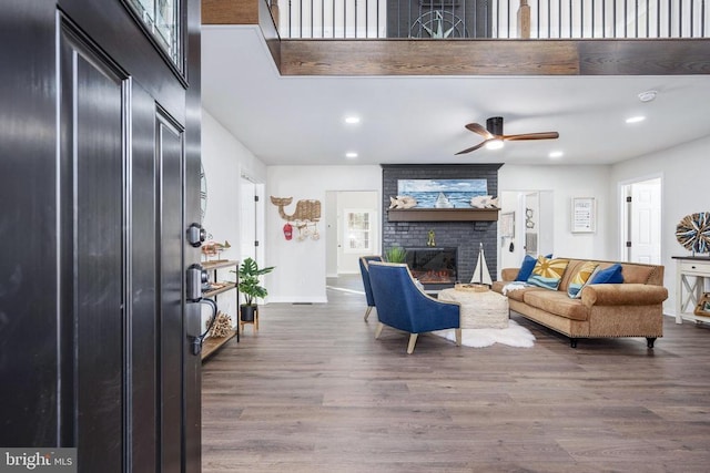 living room with a brick fireplace, baseboards, wood finished floors, and recessed lighting