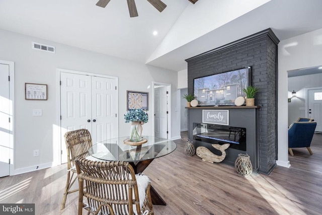 dining room with ceiling fan, high vaulted ceiling, wood finished floors, visible vents, and baseboards