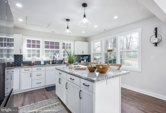 kitchen featuring dark wood finished floors, a sink, backsplash, and baseboards