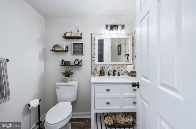 bathroom featuring baseboards, vanity, toilet, and wood finished floors