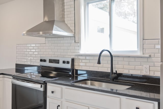 kitchen with electric stove, sink, white cabinets, and wall chimney exhaust hood