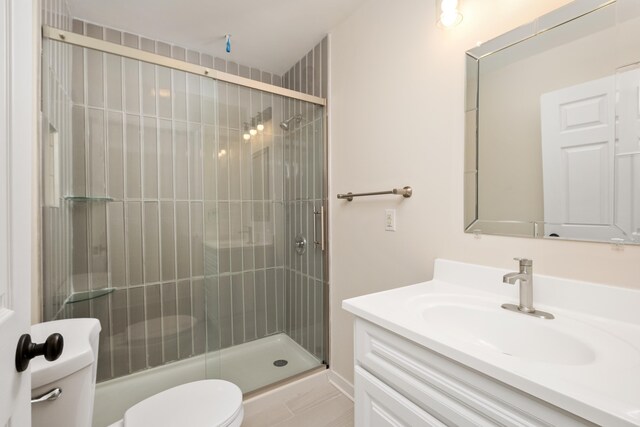 bathroom featuring vanity, a shower with shower door, and toilet