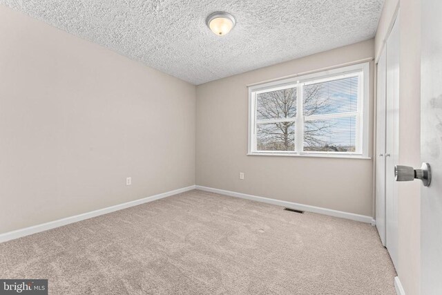 carpeted empty room featuring a textured ceiling