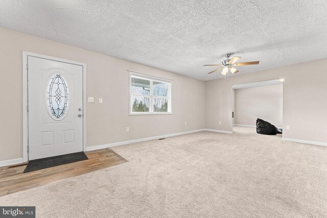 carpeted foyer with a textured ceiling and ceiling fan