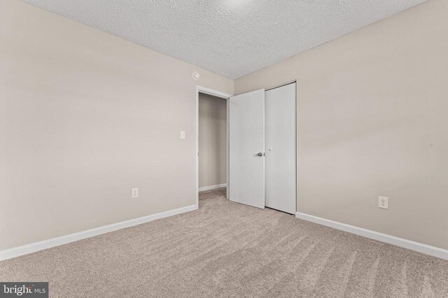 unfurnished bedroom with a closet, a textured ceiling, and carpet