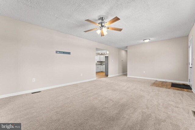 unfurnished living room with light carpet, a textured ceiling, and ceiling fan