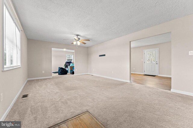 unfurnished room with ceiling fan, light colored carpet, and a textured ceiling