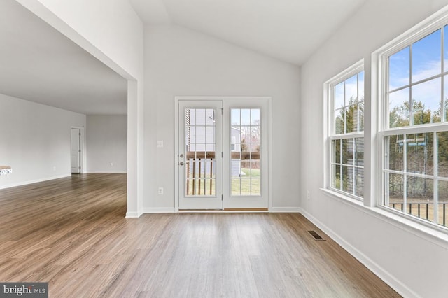 empty room with wood-type flooring and vaulted ceiling